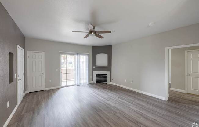 A spacious room with a ceiling fan and wooden flooring.