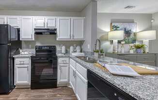 A kitchen with black appliances and white cabinets.