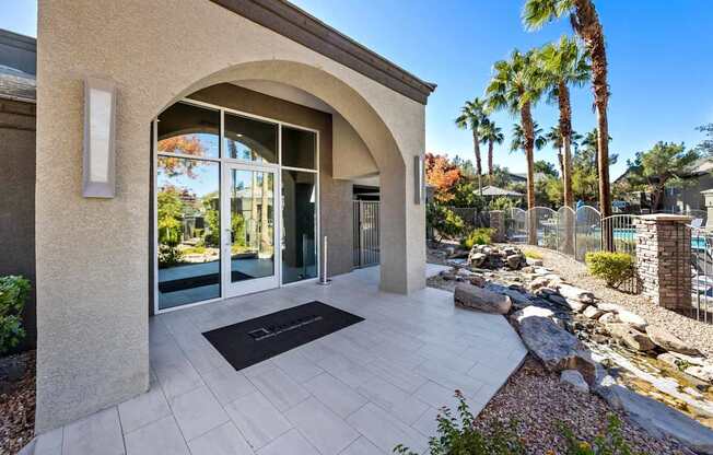 A modern house entrance with a stone wall and a black doormat.