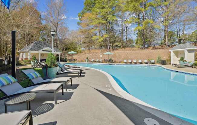 A pool surrounded by trees and a gazebo.