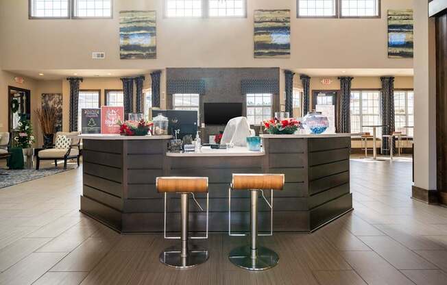 A reception area with a bar and two stools.