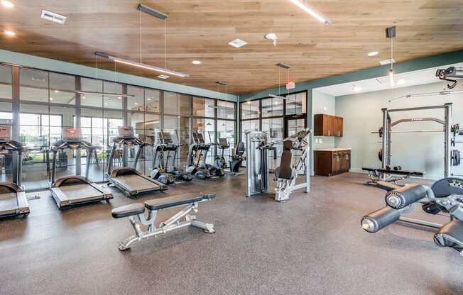 A gym with a variety of equipment including treadmills, weights, and exercise machines.