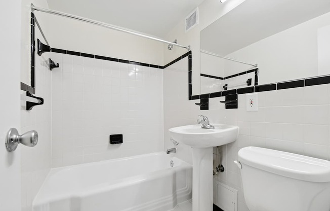 A white bathroom with a tub, sink, and mirror.