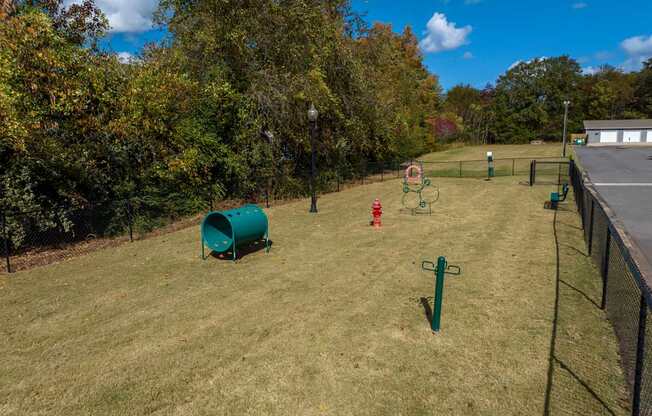 A playground with a green barrel and a red slide.