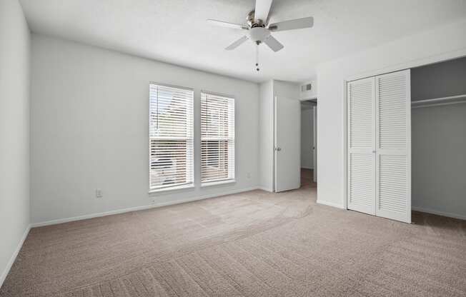 an empty living room with a ceiling fan and a closet