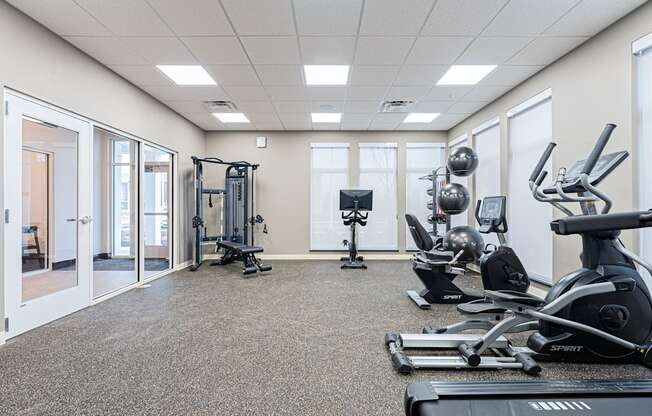 A spartan room with a treadmill, weights and exercise equipment.