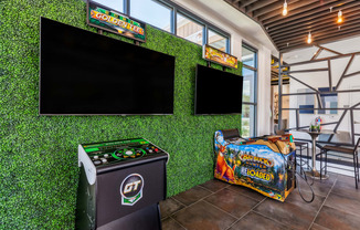 a game room with green astroturf and flat screen televisions