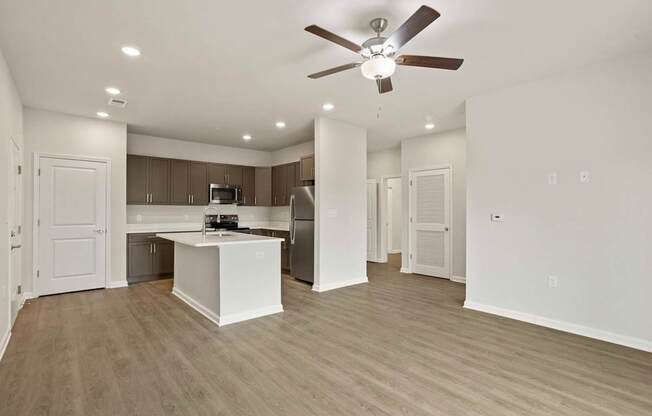 A spacious kitchen and living room with a ceiling fan.