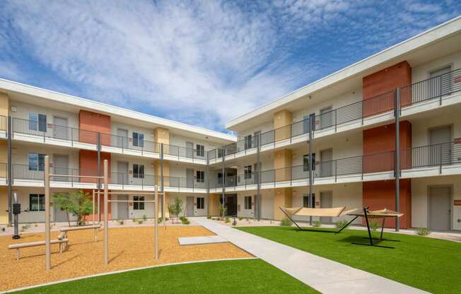 a courtyard with a picnic table and benches in front of an apartment building