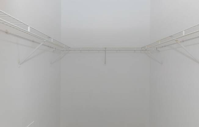 a corner of a room with white walls and a white wire rack hanging from the ceiling