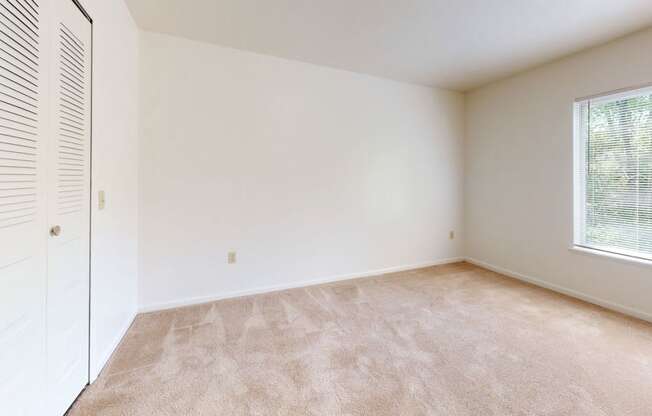 an empty bedroom with a closet and a window