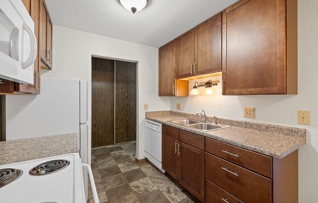 A kitchen with brown cabinets and a white dishwasher.