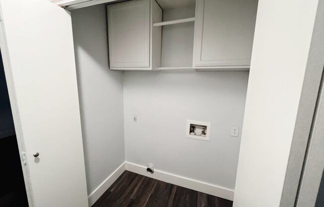 a room with white cabinets and a white wall and wooden floors