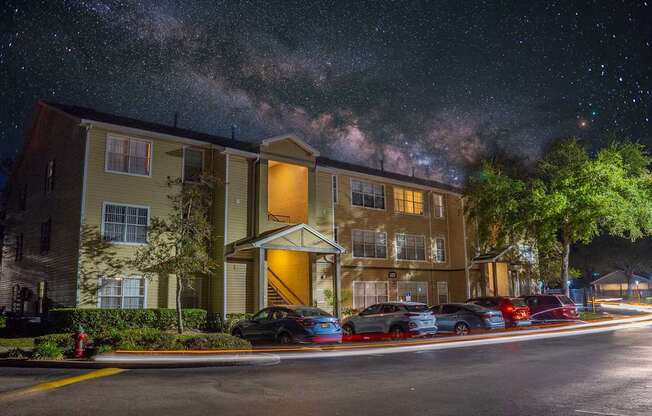 A building with a parking lot in front of it at night.