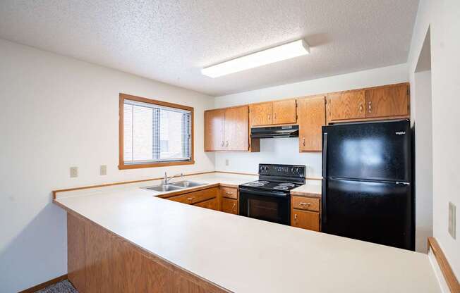A kitchen with black appliances and wooden cabinets. Fargo, ND Westwood Estates
