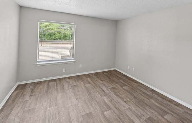 A room with a window and wooden flooring.