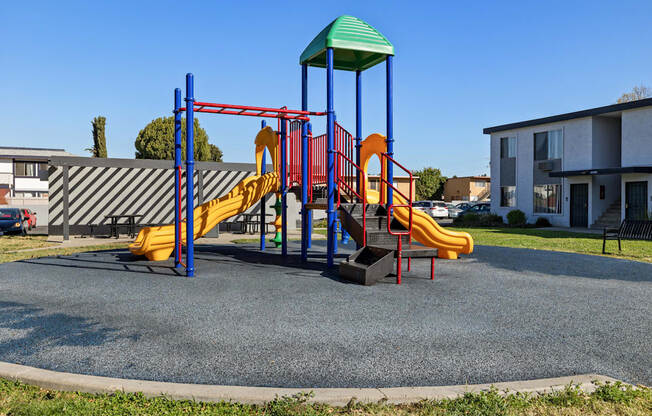 A playground with a yellow slide and a green roof.