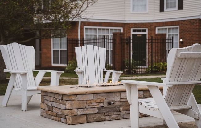 a patio with chairs and a fire pit in front of a house