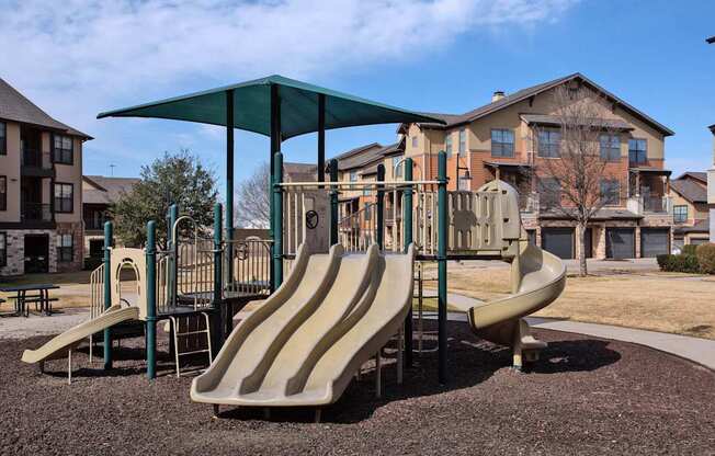 A playground with a green canopy and a slide.