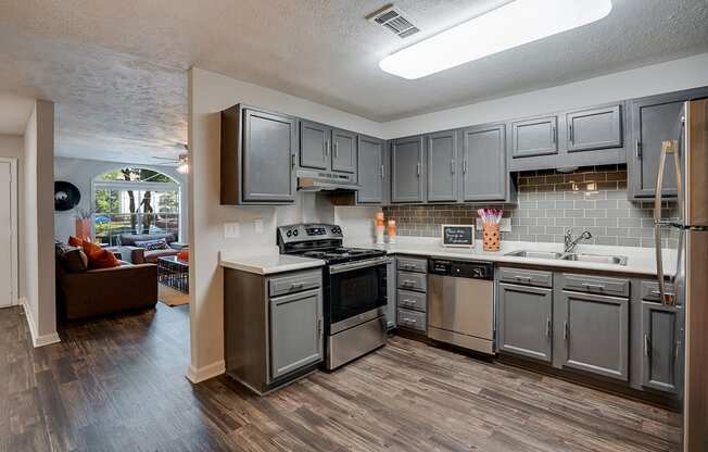 Kitchen Area Opening up to Living Room with Grey Hardwood Style Flooring