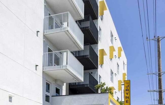 A white building with a yellow stripe and balconies.