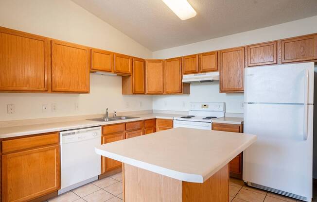 A kitchen with wooden cabinets and white appliances. Bismarck, ND Sierra Ridge Apartments