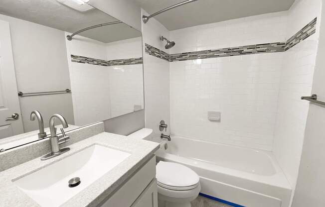 A white bathroom with a sink, toilet and bathtub.