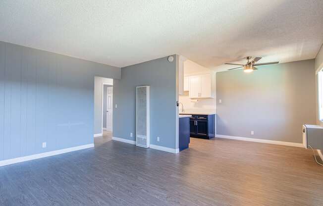 A spacious room with a ceiling fan and a kitchenette.