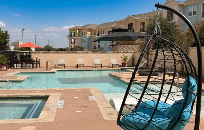 A black hanging chair is in the foreground of a pool area.