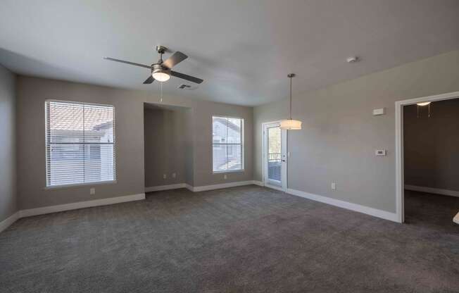 an empty living room with a ceiling fan and window