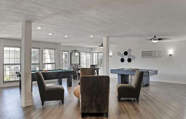 A room with a pool table and chairs.