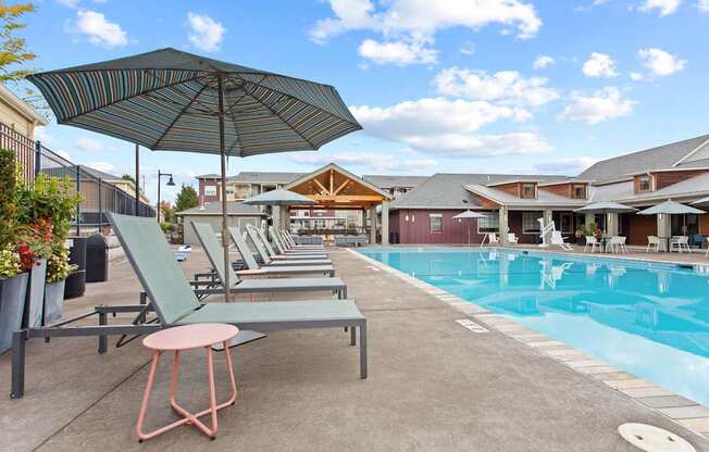 A poolside area with lounge chairs and an umbrella.