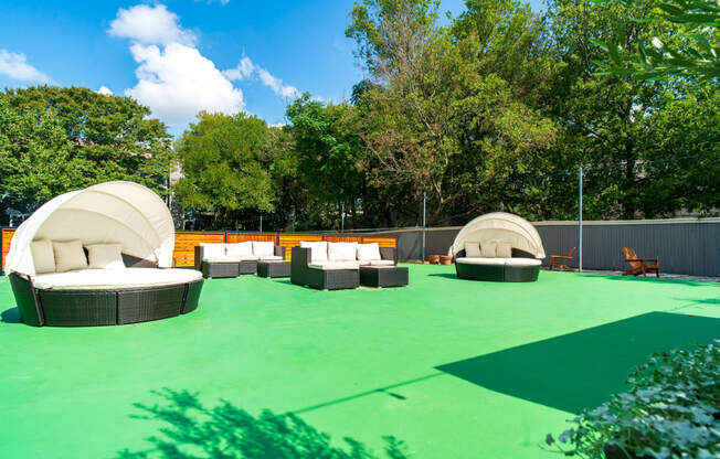 a rooftop lounge area with couches and chairs on a green court
