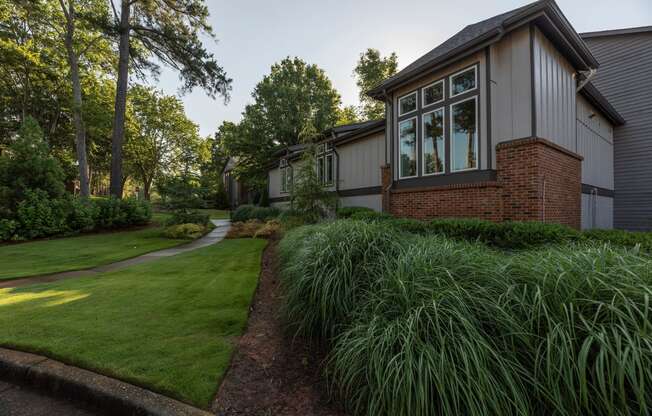 the side of a house with a lawn and a sidewalk