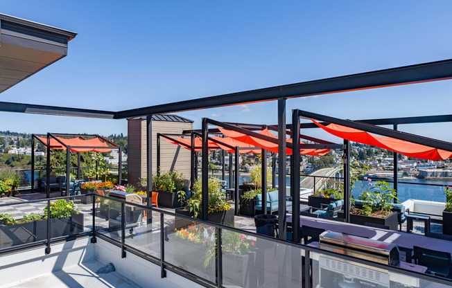a terrace with orange umbrellas and tables on a balcony overlooking the water at Spyglass Hill Apartments, Bremerton, WA