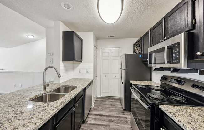 A kitchen with black cabinets and granite countertops.