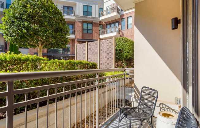 A balcony with a chair and a tree in front of a building.