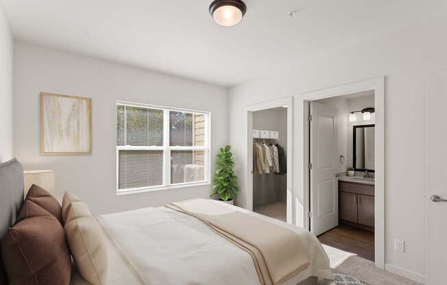 A bedroom with a bed, a mirror, and a plant.