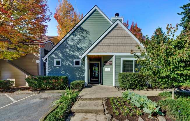 the front of a green house with a sidewalk in front of it