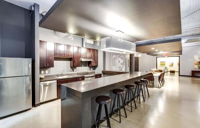 A modern kitchen with a long counter and stools.
