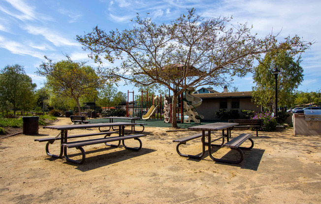 a picnic area with benches and a playground in a park