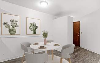 A dining room with a table set for two and two cactus pictures on the wall.