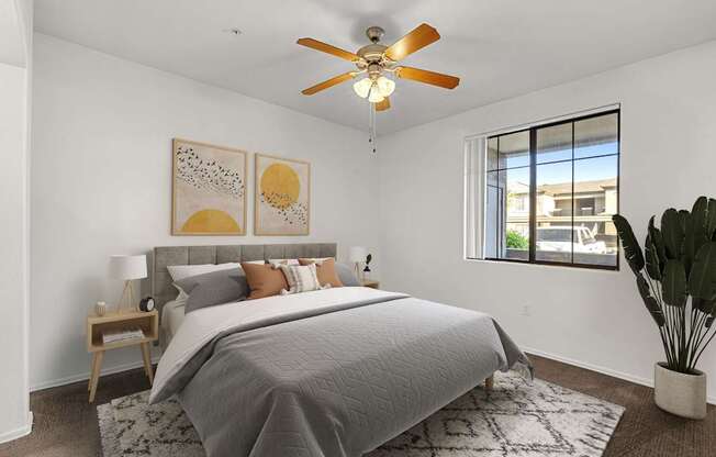 A bedroom with a bed, a ceiling fan, and a window.