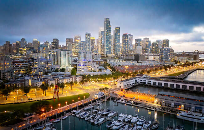 A cityscape at dusk with a marina full of boats.