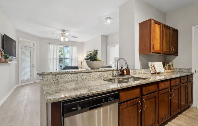 luxury kitchen with granite countertops open to a spacious living room with a ceiling fan at Sorelle apartments