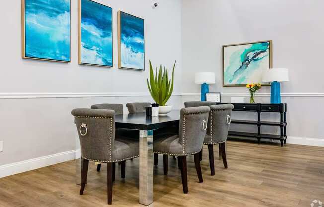 a dining room with a table and chairs and paintings on the wall  at The Park at Chesterfield Apartment Homes, Tampa