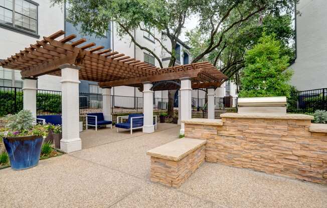 a patio with a stone wall and a pergola