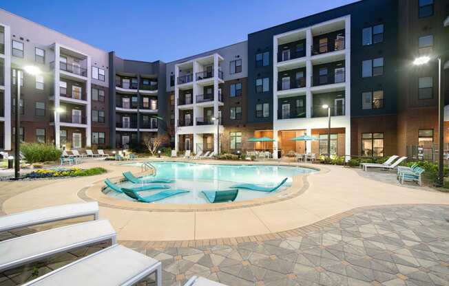 a swimming pool in front of an apartment building at night