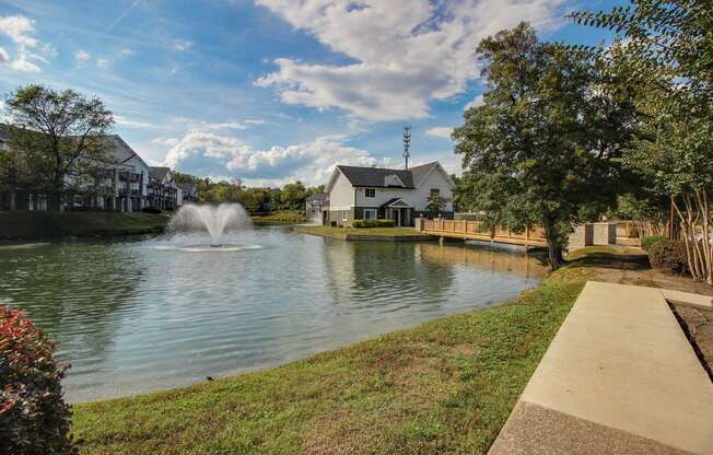 a pond with a fountain and houses on the side of it