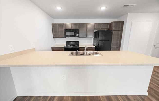 a kitchen with a large counter and a black refrigerator  at Union at Wiley, Cedar Rapids, IA